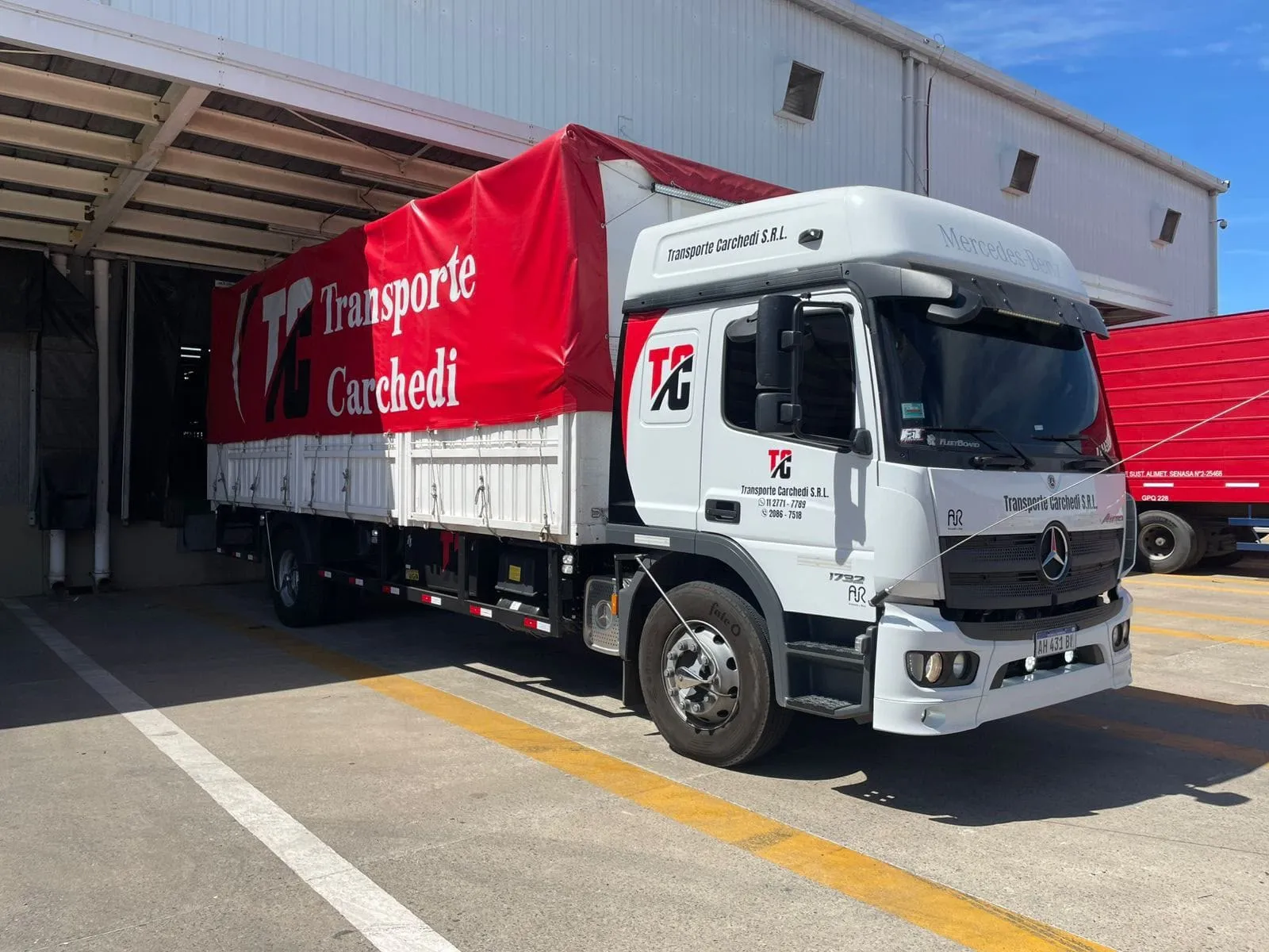 Mercedes-Benz Atego 1732 de Transporte Carchedi con lona roja, cargando en un depósito