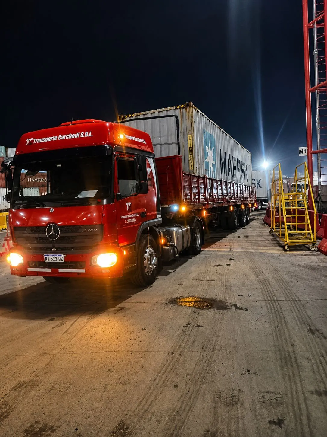 Camión de Transporte Carchedi con semirremolque y contenedor, operando de noche en el puerto