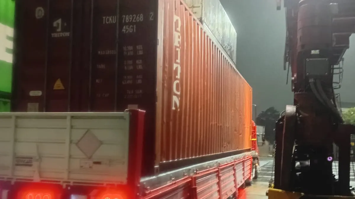 Semirremolque de Transporte Carchedi con rombo de riesgo, operando junto a contenedores