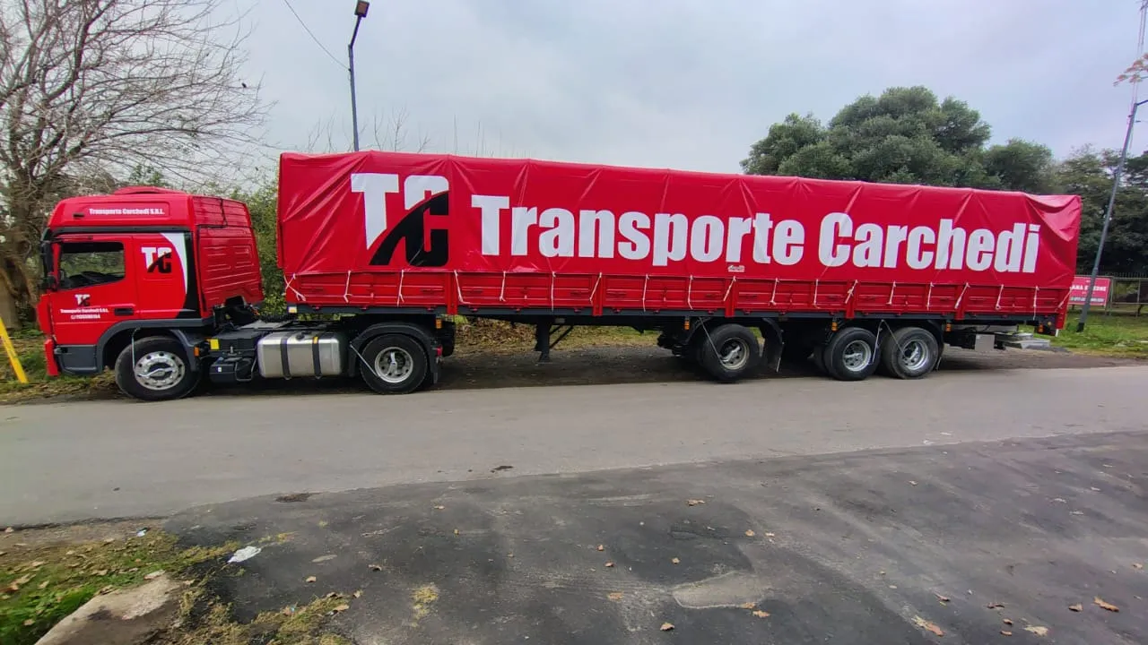 Semirremolque de Transporte Carchedi con lona roja y el nombre de la empresa a lo largo